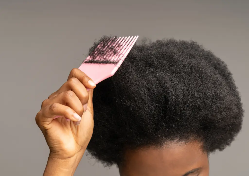 Femme afro qui peigne ses cheveux crépus